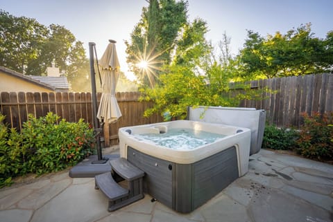 This private outdoor spa features a modern hot tub on a beautiful stone patio, surrounded by lush greenery.
