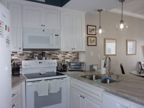 A full kitchen under cabinet lighting and granite.