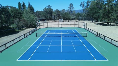 Tennis court with 2 pickleball courts and basketball hoop.