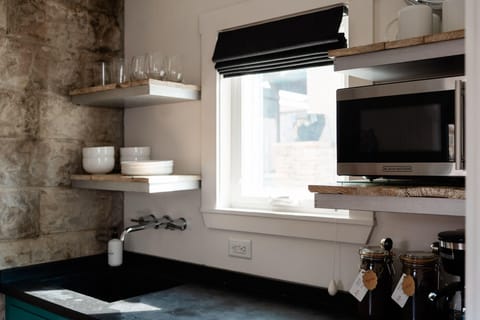 Kitchenette with essentials – microwave, sink, dishware, and coffee.