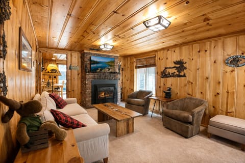 Your cozy retreat features warm wood-paneled walls, plush seating, and a stone fireplace. Rustic decor and soft lighting create the perfect ambiance for relaxing after your mountain adventures.
