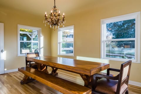 Dining Room - Dining Table with bench seating and two comfy chairs. Beautiful chandelier adorns the room.