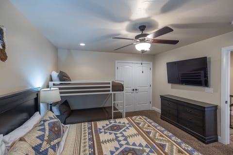 Bedroom 5 Side View - Bedroom 5 has a king bed with twin over twin bunk bed and a 55 inch TV. There are power stations on the nightstands with power outlet and USB ports for easy charging or power access.