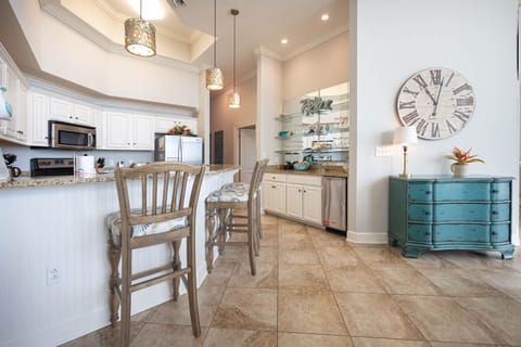 The coastal kitchen features stainless appliances, granite countertops, and stylish lighting, perfect for culinary adventures