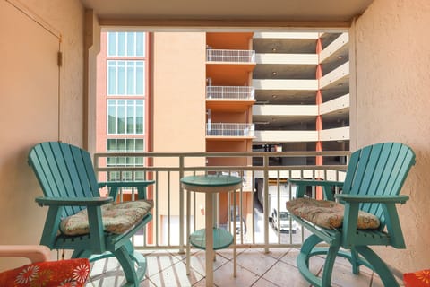 The balcony features cheerful turquoise chairs and a small table, offering a spot to enjoy the view of the surrounding area