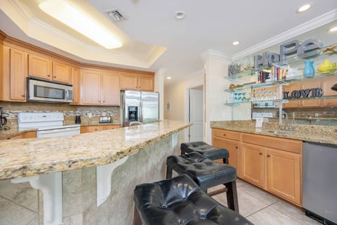Inviting kitchen featuring granite countertops, white and stainless appliances, and stylish bar seating for a cozy gathering