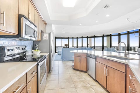 This modern kitchen features stainless appliances, sleek cabinetry, and a stunning beachfront view through expansive windows