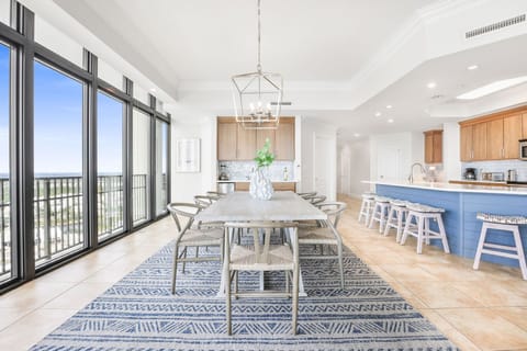 This bright dining area features a large table with eight chairs, and a view through expansive windows, perfect for gathering