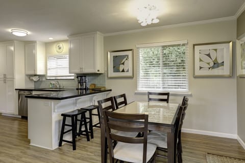 Charmingly designed dining area, comfortably accommodating six guests around the table, complemented by stylish bar stools at the kitchen counter for additional seating options.