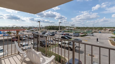 The master balcony view showcases a bustling parking lot with a mix of cars and a glimpse of nearby recreational facilities