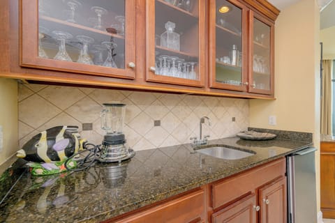 Charming wet bar area features a stylish granite countertop, a blender, ice-maker, and decorative glassware