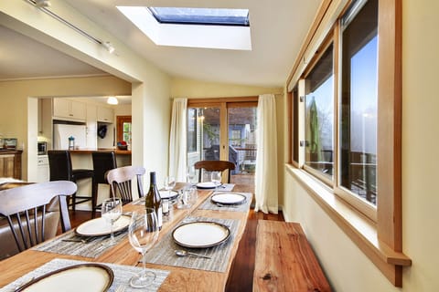The dining table is surrounded by light - windows, doors, and skylights.