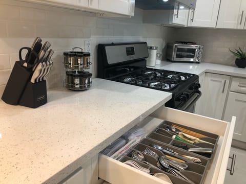 Fully stocked kitchen with spices, utensils, silverware, and cutlery.