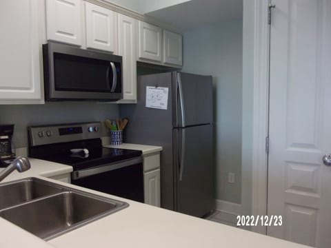 Glass top electric range with microwave above, and refrigerator/ice maker.