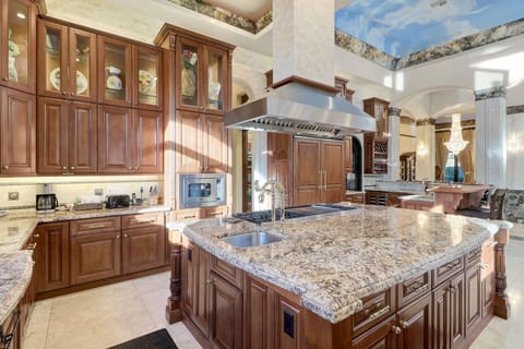 Kitchen w/ large double door paneled fridge, built-in microwave, & large cooktop