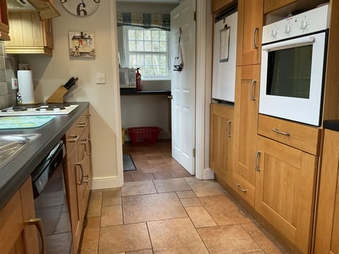 Kitchen leading to utility room with washer/dryer and airing cupboard.