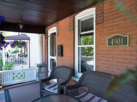Front porch with outdoor furniture overlook a green space across the road