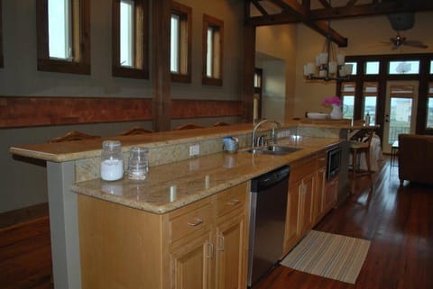 kitchen island with sink, microwave, dishwasher and long bar for dining
