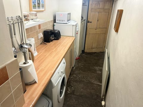 Well-equipped kitchen contains electric cooker, microwave and washing machine 