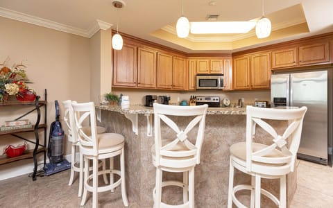 This kitchen features warm wood cabinetry, granite countertops, and a cozy breakfast bar, perfect for morning coffee