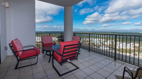 Relax on the balcony with red cushioned chairs and a table, enjoying the serene state park view from the eighteenth floor