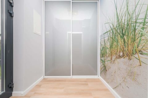 A bright hallway with a large wardrobe and light wooden floors and access to many rooms, creating a welcoming transition area in the house.