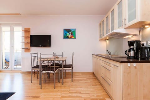 Another shot of the living room, this time seen from a different angle. Part of the kitchen is in the background, and the dining table with four chairs is visible in the foreground. The interior decoration is bright and modern.