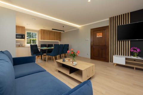 A large, bright open living space with modern furniture, sleek wooden flooring, and a mix of soft and bold décor elements, designed for relaxation and entertainment.