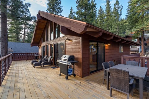 Expansive deck with outdoor dining and lounge seating has charcoal and gas grill