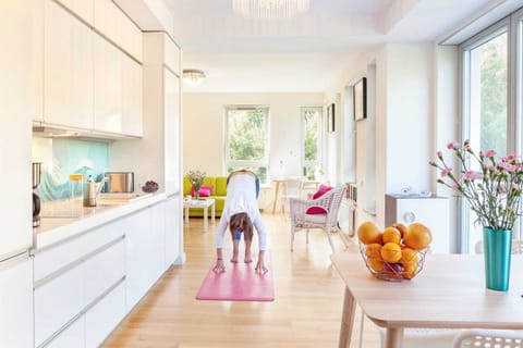 A spacious kitchen with a dining area decorated with fresh flowers on the table. Large windows allow natural light to flood in, creating a welcoming, cheerful atmosphere.
