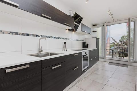 Kitchen with dark melbls and oven. From the kitchen you can access the balcony.