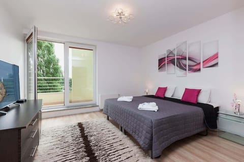 A bright bedroom with a large window, double bed, bedside tables, and simple decor.