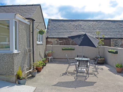 Pretty courtyard with garden furniture and BBQ | Ty Main Cottage, Newborough, near Llangefni