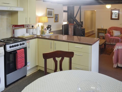 Fully equipped kitchen with dining area within the open-plan design | The Den - Ty Copr, Pen-y-Sarn, near Amlwch