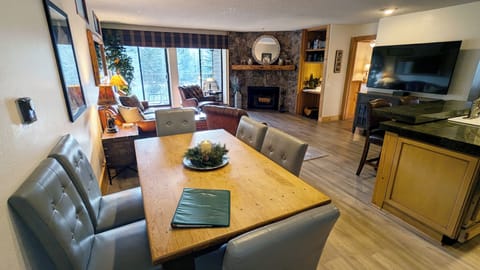 Living room with wood fireplace, dining table, and balcony w/ propane BBQ grill