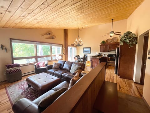 Great room with vaulted ceiling, leather sofas, dining & kitchen; deck access.