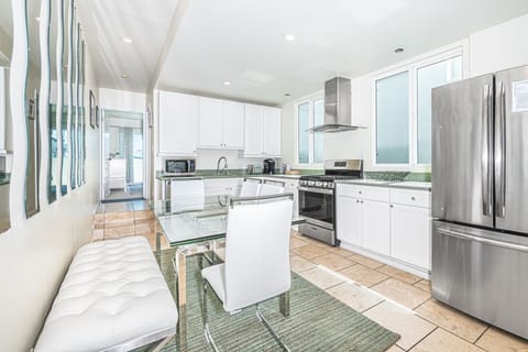 Dining table with bench and chair seating sits within the kitchen on one side and the central staircase on the other. Located on middle (main level).