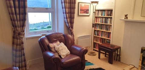 Sitting room with the very full bookcase with two rows of books on each shelf.