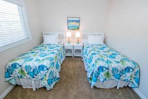 Fourth bedroom outfitted with two twin beds, linens, carpeting and closet. Located along central hallway.