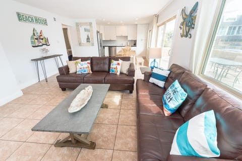 The main living area includes a sofa set, cable TV, and sliding glass doors that open up to the expansive front patio.
                