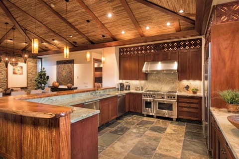 CHEF'S KITCHEN WITH HIGH-END APPLIANCES. KOA WOOD BAR AND STONE COUNTERTOPS