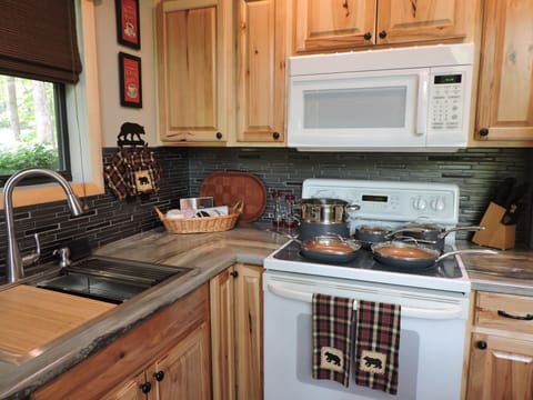 Smooth top stove with new pots and pans and microwave. Fridge to the right.