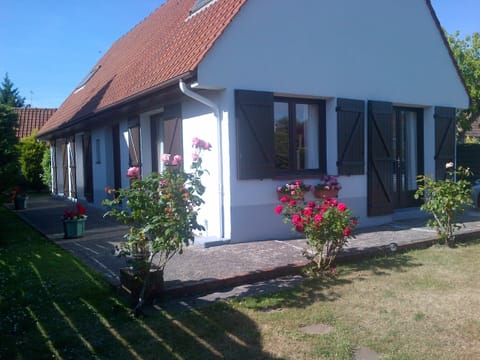 Front of house with south-facing patio and small grass lawn to  hedge