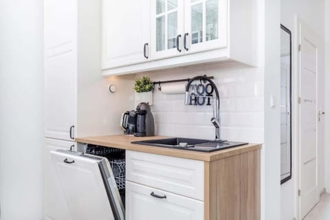 A compact kitchenette with white cabinetry, a wooden worktop, and a coffee maker, blending functionality with a minimalist design.
