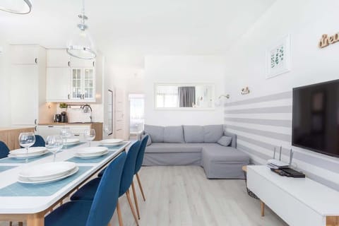 An open-concept living room with a sofa, dining area, and large windows, giving a spacious and comfortable feel.