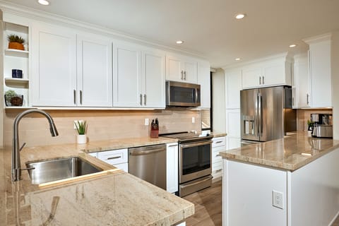 The kitchen has been just been remodeled with granite counters, custom cabinetry, stainless appliances, wood-look porcelain floors, and recessed lighting.