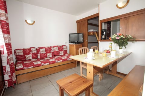 The 1 Bedroom Apartment at Residence le Hameau du Borsat by Odalys offers a bright living space with a comfortable sofa and a dining table