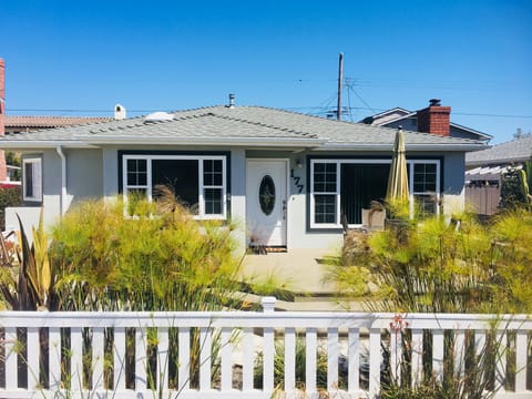 White picket fence, front porch with table and chairs, gas BBQ