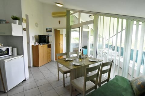 Living area with TV and dining table with 4 chairs, sofa bed and exit to the balcony