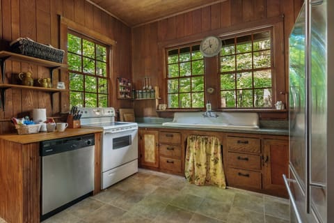 Prepare meals with a gorgeous WOODED VIEW and a winter LAKE VIEW. Features old farmhouse sink, electric stove / oven, dishwasher, microwave (not shown, on rear wall) and refrigerator / freezer.